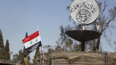 A Syrian national flag flutters next to ISIS's slogan at a roundabout where executions were carried out by ISIS militants in Palmyra. Omar Sanadiki