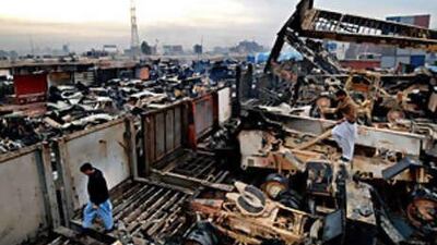 Pakistani employees inspect the smoldering trucks at a Nato terminal outside the north-western city of Peshawar.