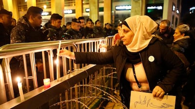 An anti-government protester holds an Arabic placard that reads: "You even stole the dream," as she lights a candle in front the riot police. AP