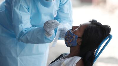 A healthcare worker wearing personal protective equipment (PPE) takes a swab sample from a woman for the coronavirus disease (COVID-19) in Cantagallo, an indigenous Shipibo-Conibo community, during the vaccination campaign against the coronavirus, in Lima, Peru. Reuters