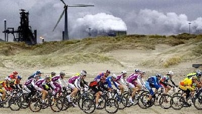 Cyclers, taking part in the 9th Egmond-Pier-Egmond ATB-Beach Race, pass in front of the Anglo-Dutch steel-factory Corus in the town of Wijk aan Zee.