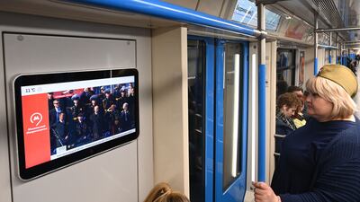 Commuters watch a broadcast of the parade on a metro train in Moscow. AFP