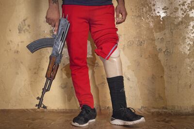 Hassam Naeem, 22, a former PMU fighter was injured during a military operation against ISIS. Amputee and jobless, Hassam poses with a Kalashnikov rifle at his parents' house, in Basra. Photo by Sebastian Castelier
