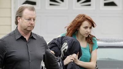 A woman believed to be Amanda Knox, centre, is hidden under a jacket while being escorted from her mother’s home to a car by family members on Thursday. AP Photo