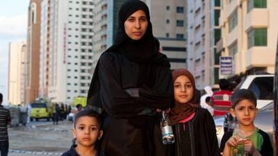 Sana Bawadi and her children, from left, Abdullah, Lian and Ismail, wait in the street while firefighters tackle the flames in the Al Aneeqa Tower in Sharjah.