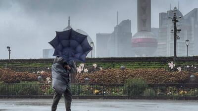 A pedestrian struggles to control their umbrella along the Bund in Shanghai.