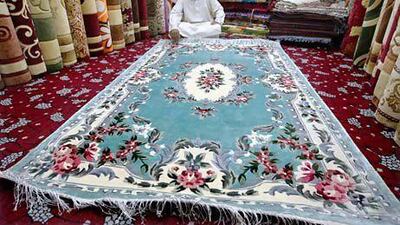 Abdullah Khan, a trader, sits with an Iranian carpets at the Abu Dhabi carpet souq. Stephen Lock / The National