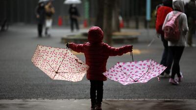 A young girl holds a pair of umbrellas in the rain at a park in Tokyo. Eugene Hoshiko / AP photo