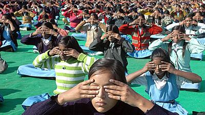 School children perform yoga exercises while participating in a mass ‘Surya Namaskar’ (Sun Salutation) during National Youth Day in Bhopal, Madhya Pradesh, India, yesterday.