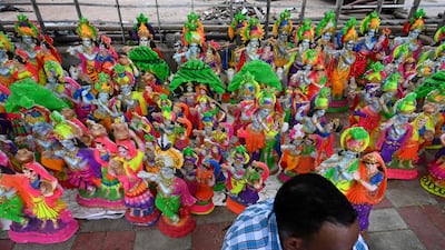 A vendor waits for customers as he sits next to idols of Krishna along a roadside in New Delhi. AFP