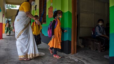 A teacher guides children to their classroom.