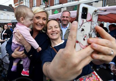 Marine Le Pen poses for a selfie with a mother and child during campaigning in Henin-Beaumont, northern France. AFP