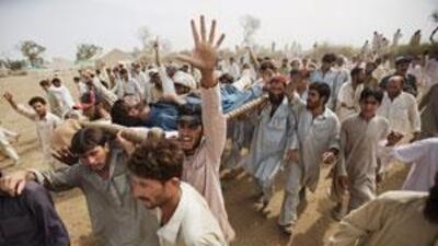 An angry mob carries a man from Swat - bystanders say he was beaten by police after asking fro his food rations.
