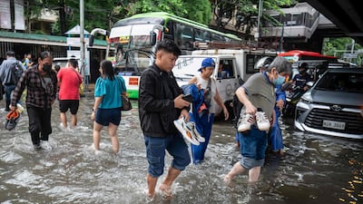 Pedestrians cross a flooded street after heavy rain in Manila. AFP