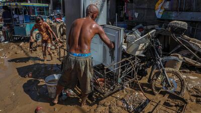 Gary Villanueva cleans their refrigerator as his wife Amy salvages other belongings in the aftermath of Typhoon Vamco in Rodriguez, Rizal. EPA
