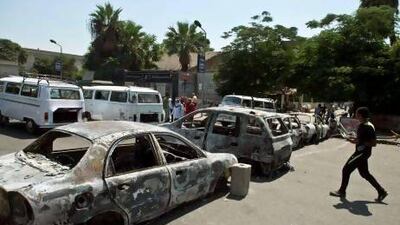 An Egyptian man passes by burnt out cars near Cairo University where supporters of Egypt's deposed president Mohammed Morsi are holding an open sit in.