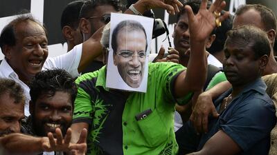 A supporter of Sri Lanka's ousted prime minister Ranil Wickremesinghe wears a mask depicting Sri Lankan President Maithripala Sirisena during a rally in Colombo. AFP