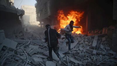 Residents move amidst rubble near a burning vehicle in a site damaged from what activists said was shelling by forces loyal to Syria's president Bashar Al Assad in the town of Douma, eastern Ghouta in Damascus on December 30, 2015. Bassam Khabieh / Reuters