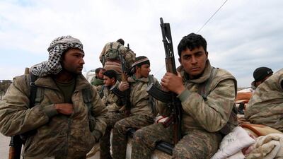 Kurdish People's Protection Units (YPG) fighters carry their weapons while riding on the back of a pick-up truck in Qamishli, Syria. Rodi Said / Reuters