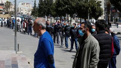 People stand in a line to buy bread after Jordan announced it would allow people to go on foot to buy groceries in neighborhood shops, in Amman, Jordan. Reuters