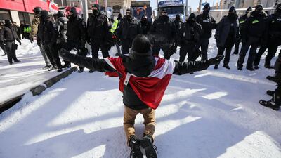 A protester kneels in front of police officers. Reuters