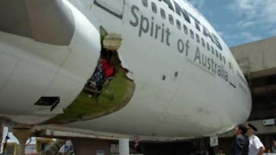 The Qantas pilot Capt John Francis Bartels, right, looks at the hole of the Melbourne-bound Boeing 747 after it made an emergency landing at the international airport in Manila.