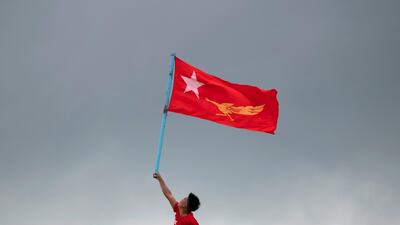 An NLD supporter holds a flag on the top of a boat as he takes part in a rally in the Yangon river. Reuters