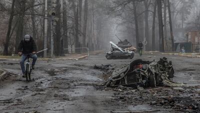 Ukrainians ride bicycles past destroyed cars in the town of Bucha, north-west of the capital Kyiv. Reuters