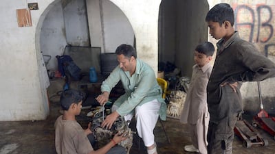 Blind Pakistani mechanic Asif Patel, second from left, working on a car engine at his workshop in Karachi. Mr Patel's story is a rare tale of success in a country which offers few opportunities for the blind. Rizwan Tabassum/AFP Photo