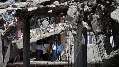 Palestinian youths observe workers on April 15, 2015 clearing the rubble of heavily damaged buildings in eastern Gaza City. Thomas Coex / AFP
