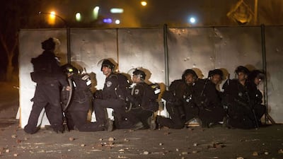 Israeli policemen take cover during clashes that erupted in the southern Bedouin town of Rahat following the funeral of Sami Al Zayadna on January 19, 2015. Menahem Kahana/AFP Photo