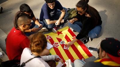 Young people play cards on a Catalan flag in Barcelona on October 10, 2017 as Catalonia's regional leader was addressing parliament in a highly anticipated session that could spell the birth of a new republic, marking a critical point in a decade-long standoff between Catalan separatists and Spain's central authorities. Francisco Seco / AP