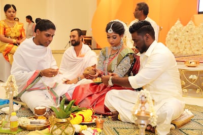 Iswarya Sundararajan and Arvindh Selvam listen as the priest explains the rituals during their wedding ceremony at the Hindu temple in Jebel Ali, Dubai. Pawan Singh / The National