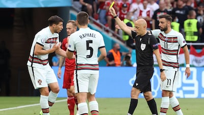 Turkish referee Cuneyt Cakir shows a yellow card to Portugal defender Ruben Dias. AFP
