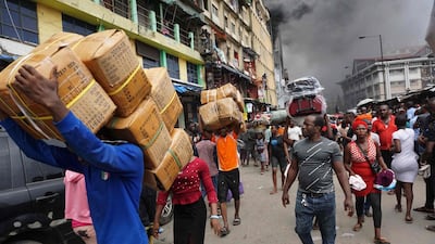 People carry boxes as they salvage goods from a seven-storey building that was on fire at the Balogun Market in Lagos, Nigeria. AFP