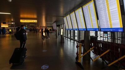 A traveller wearing a face mask checks the flight times at Schiphol Airport, near Amsterdam. AP