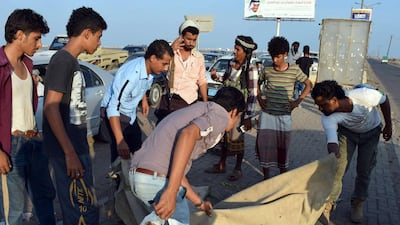 Residents of Aden look at the remains of a suicide bomber who struck at a checkpoint of the Southern Resistance in Yemen’s southern port city on October 26, 2015. Saleh Al Obeidi / AFP