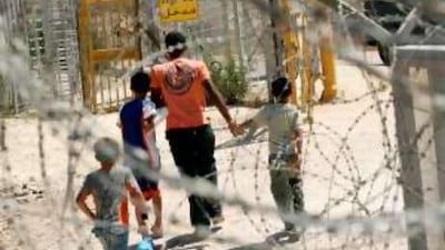 A Palestinian farmer and his children head toward a gate in an Israeli separation barrier to reach their land near the West Bank town of Qalqilya.