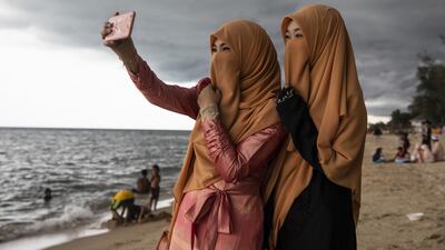 Women take a selfie on the Talo Kapo beach while marking Eid Al Fitr in Pattani, Thailand.
