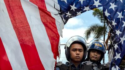 Riot police look on as Filipinos burn an American flag at a protest outside the US embassy in Manila. Getty Images