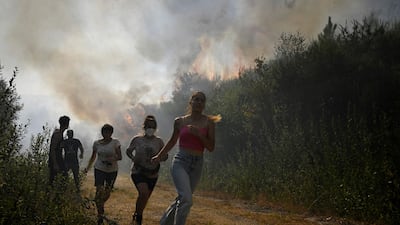 People run to escape the encroaching flames near the village of Melon, in Spain's north-west. AFP