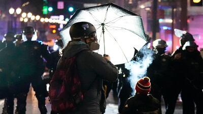 A person holds up an umbrella in front of a line of police officers during protests in Portland, Oregon. AP Photo
