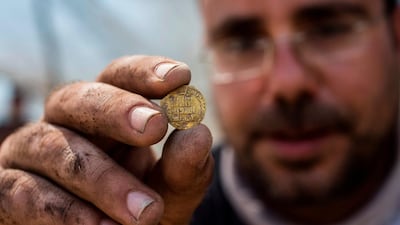 Israeli archaeologist Shahar Krispi, 35, displays a gold coin from a hoard dating to the Abbasid Caliphate discovered at an archaeological site near Tel Aviv in central Israel. AFP