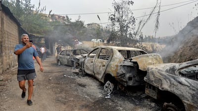 A man takes a picture of a row of burnt-out cars. EPA