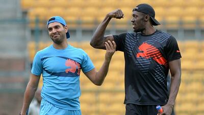 Usain Bolt flexes for Yuvraj Singh following a six during a practice session on Tuesday before their exhibition four-over cricket match. Bolt, on his first visit to India, took part in the match with some of India's top players. Manjunath Kiran / AFP