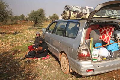 Ghossoon and her husband sit by their parked car on the outskirts of Maaret Misrin town in Syria's Idlib province on February 6, 2020. AFP
