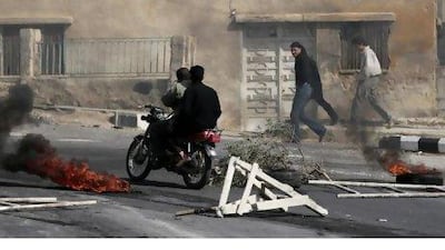 Anti-Syrian government protesters pass next to burning tyres set alight by the protesters.