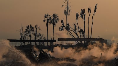A firefighter hoses down flareups at the two story Hawaiian Village Apartment complex that burnt to the ground during the Thomas wildfire in Ventura, Californi. Mark Ralston / AFP