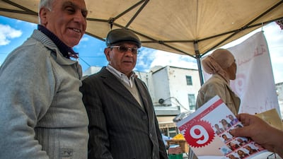 A volunteer of an independent local party gives electoral leaflets to residents in l'Ariana, outside Tunis, on May 4 2018. Hassene Dridi / AP