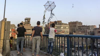 Egyptian youths fly a handmade kite from an overpass on the capital Cairo’s Ring Road before iftar at sunset. AFP
